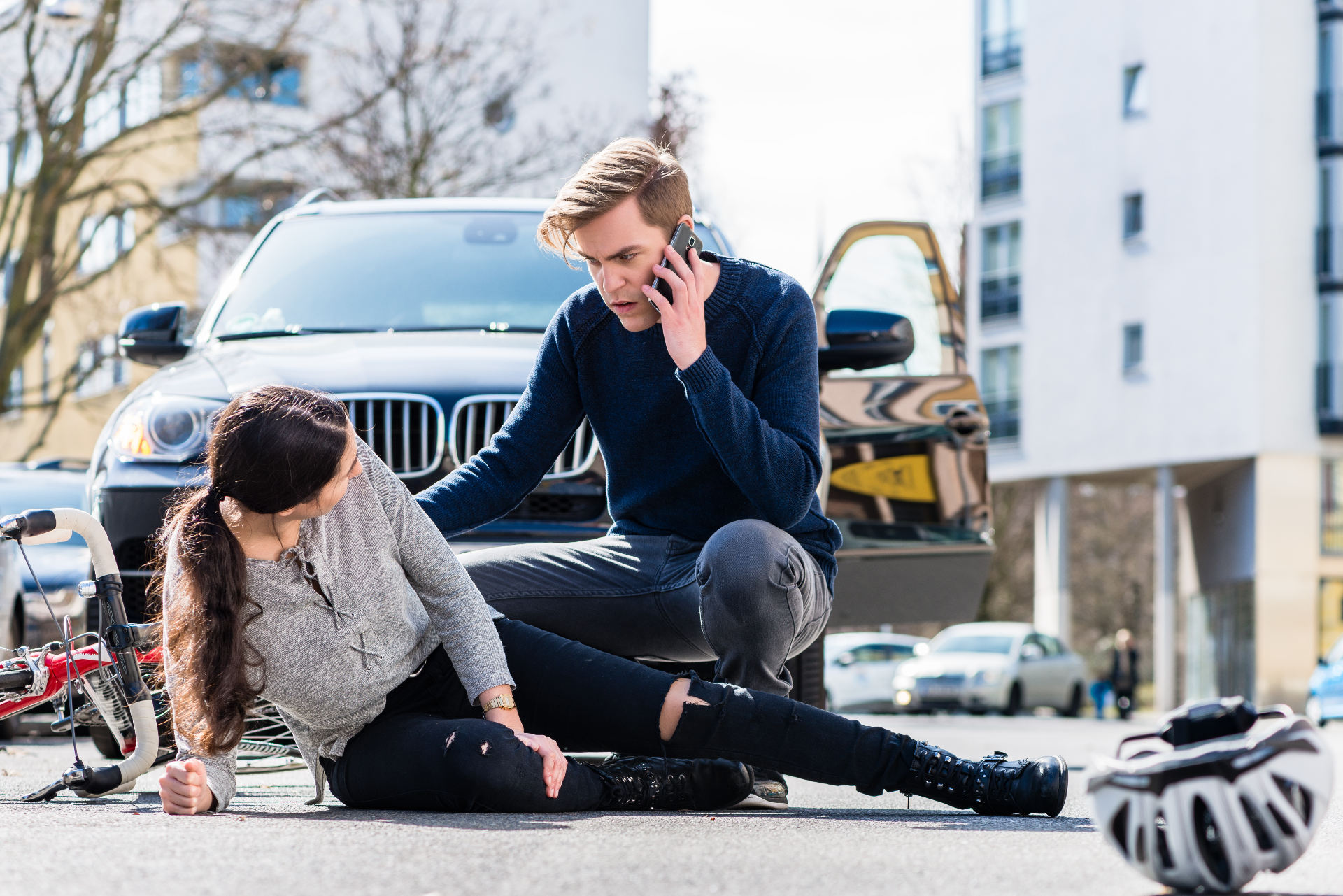 man on a cell phone with a women injured on the road