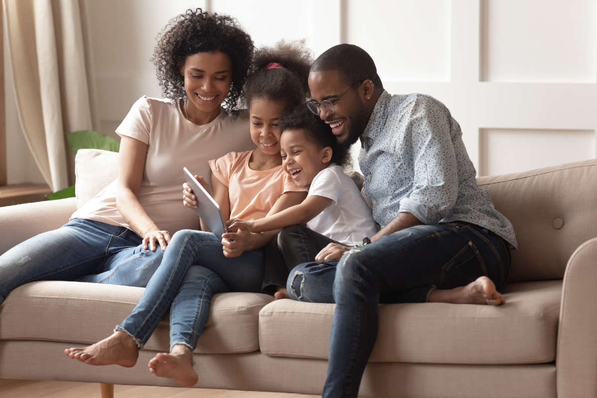 two parents sitting with two kids looking at a tablet