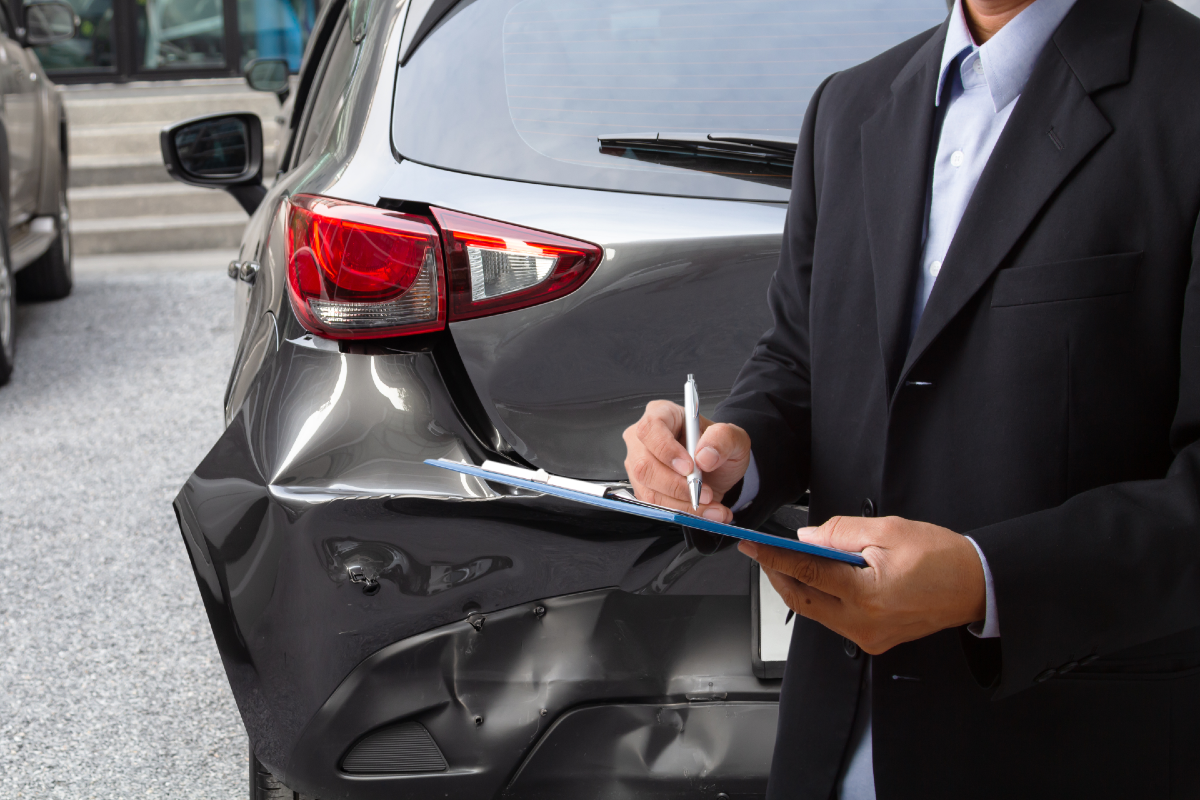 damaged car and man filling out clipboard