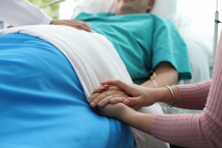 Close-up of a Patient in a Hospital Bed Having Their Hand Held