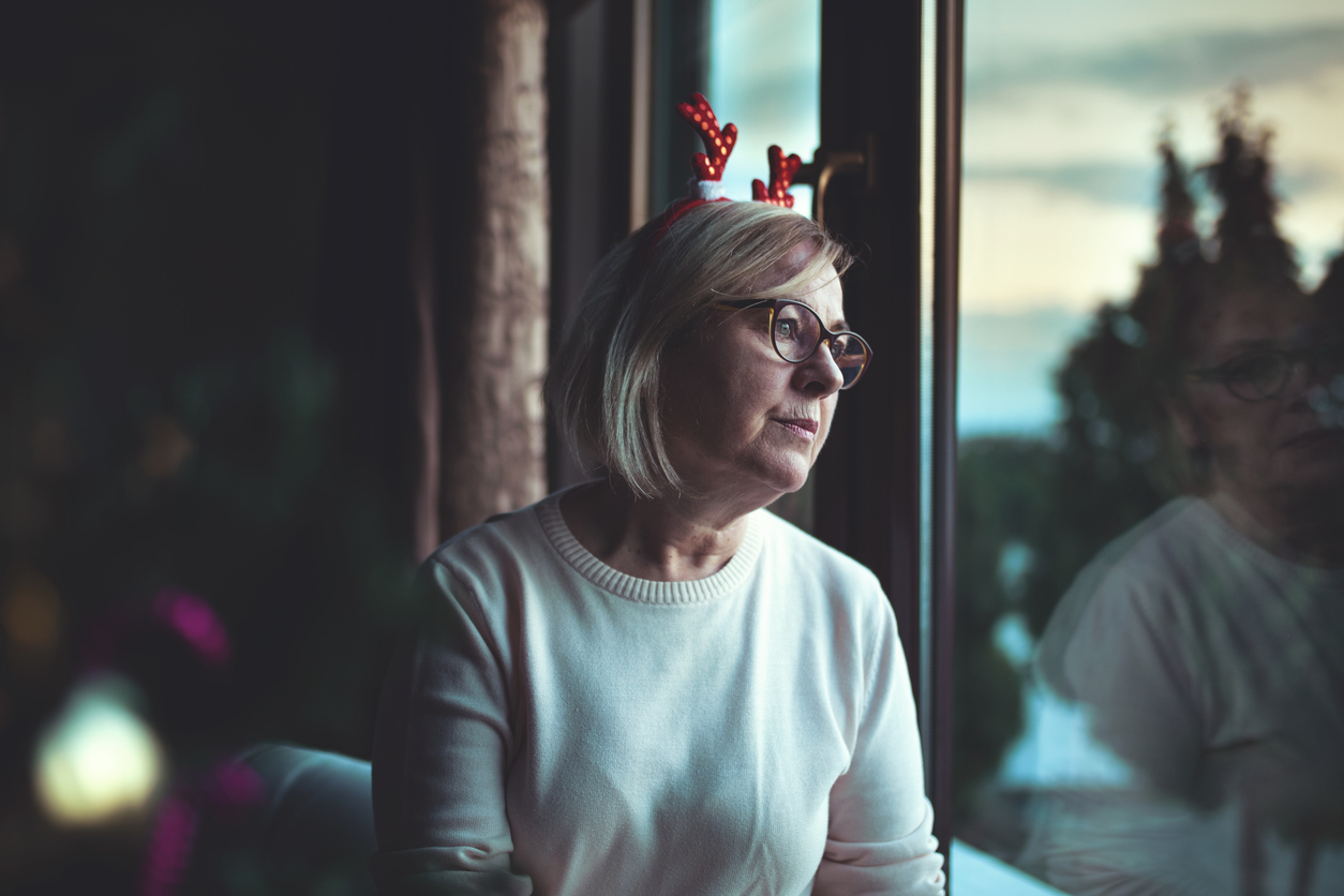 older woman staring out the window during the holidays