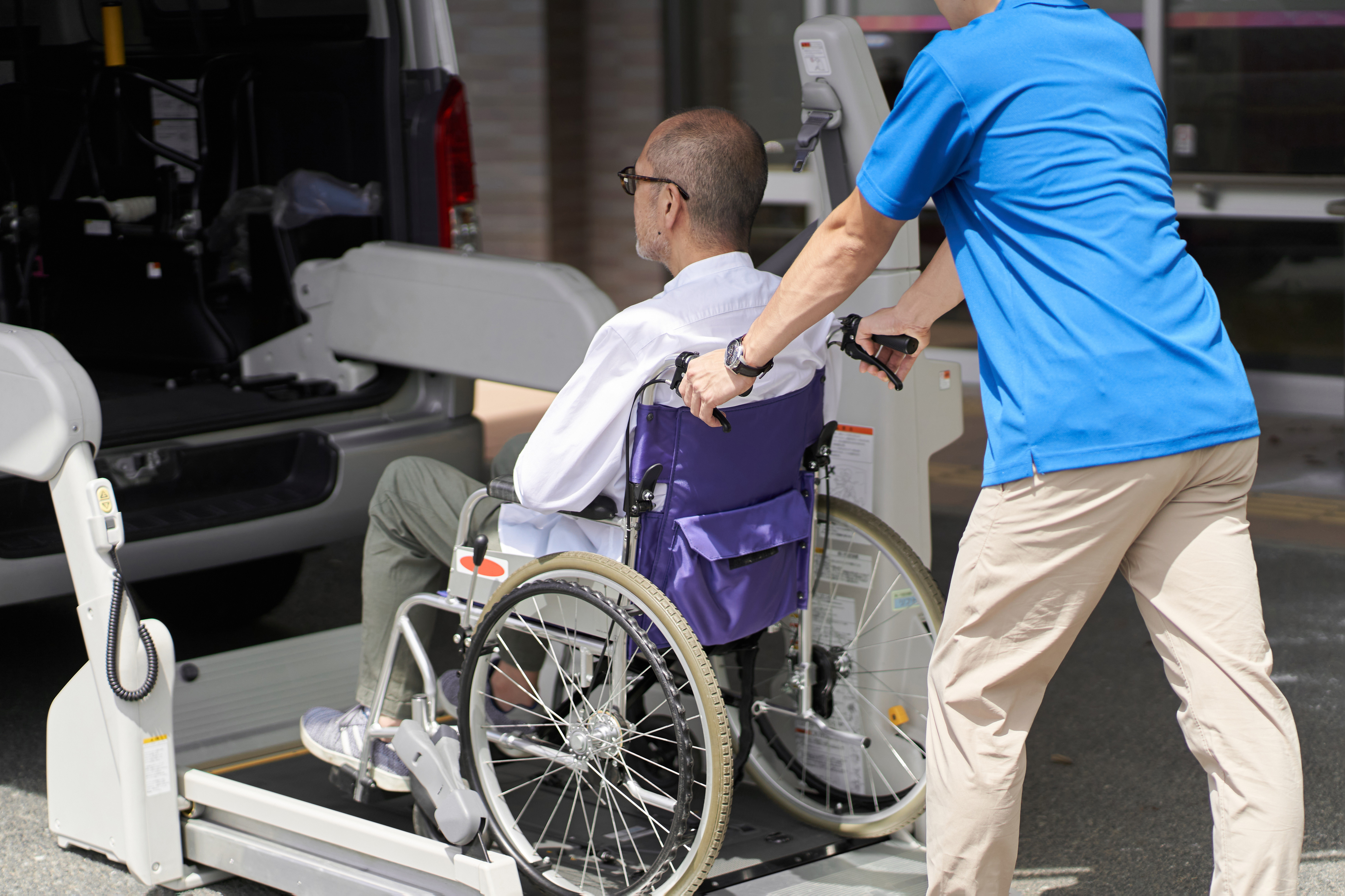 Man In A Wheelchair Being Pushed Onto A Van Chair Lift