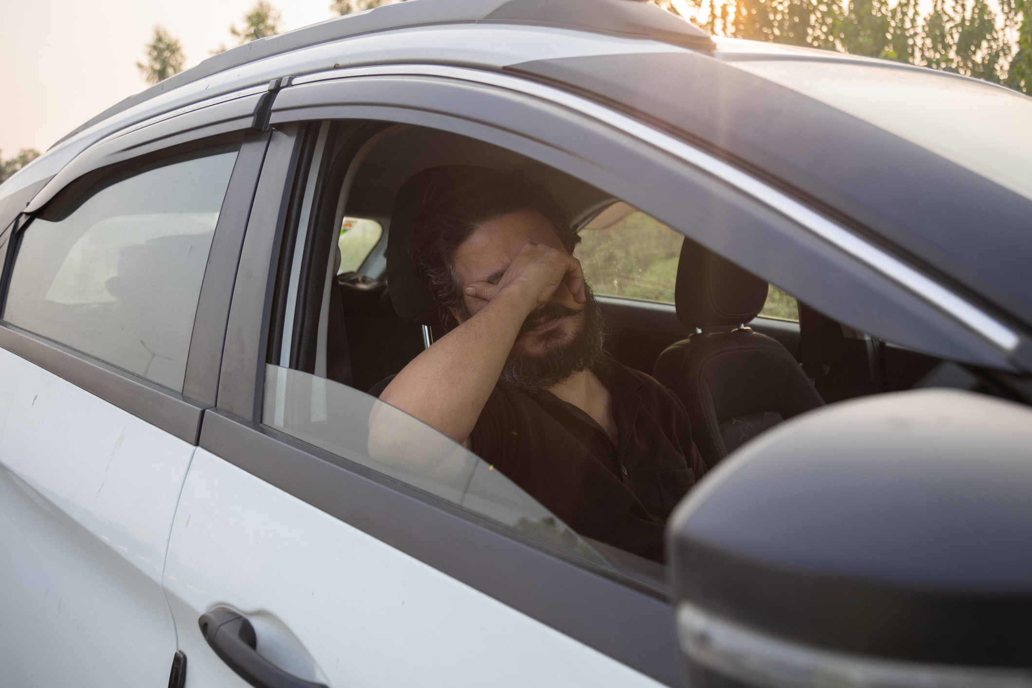 Man In Car Covering His Eyes