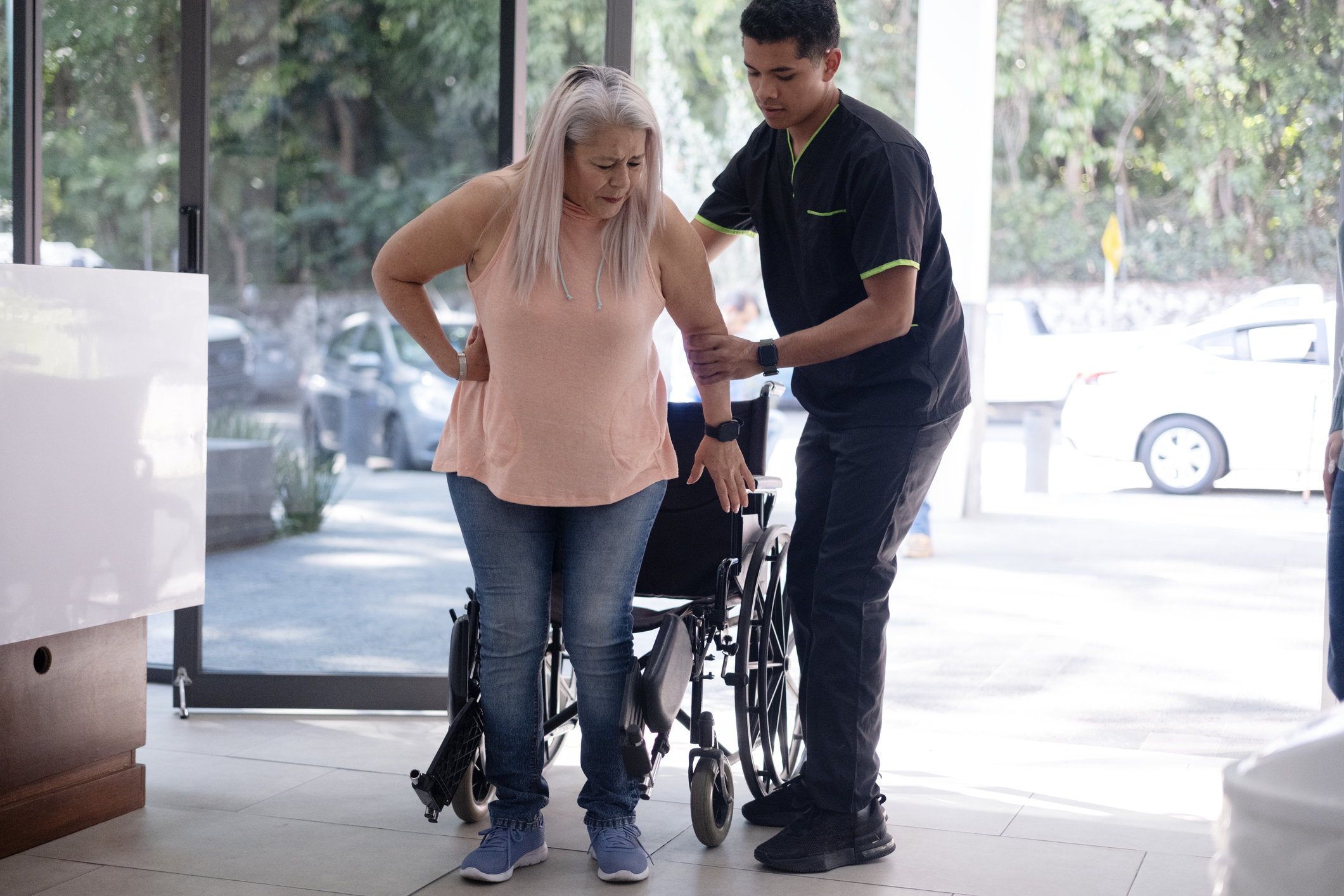Male Nurse Helps Woman Out Of Wheelchair