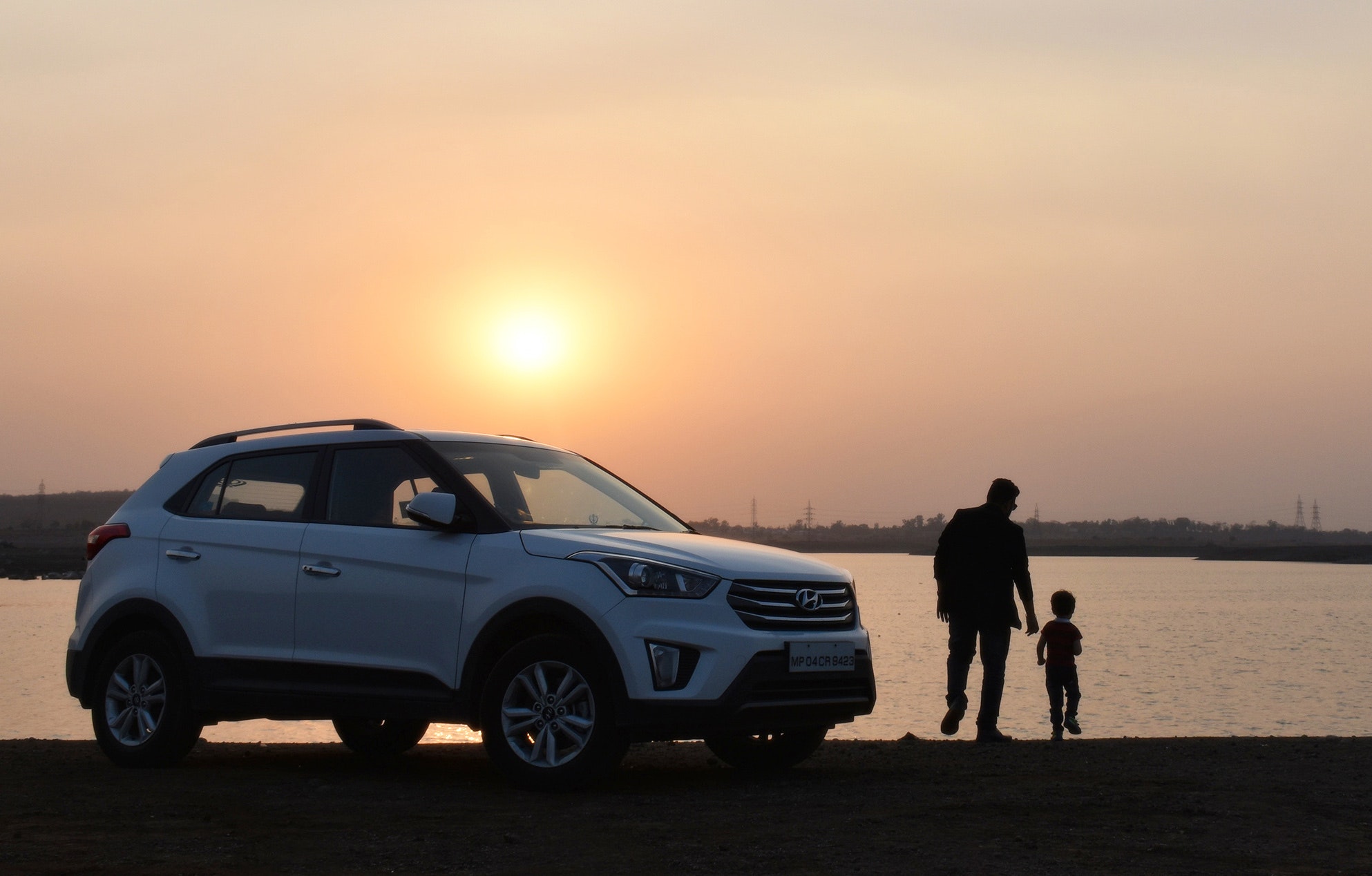 parent and child with vehicle at sunset