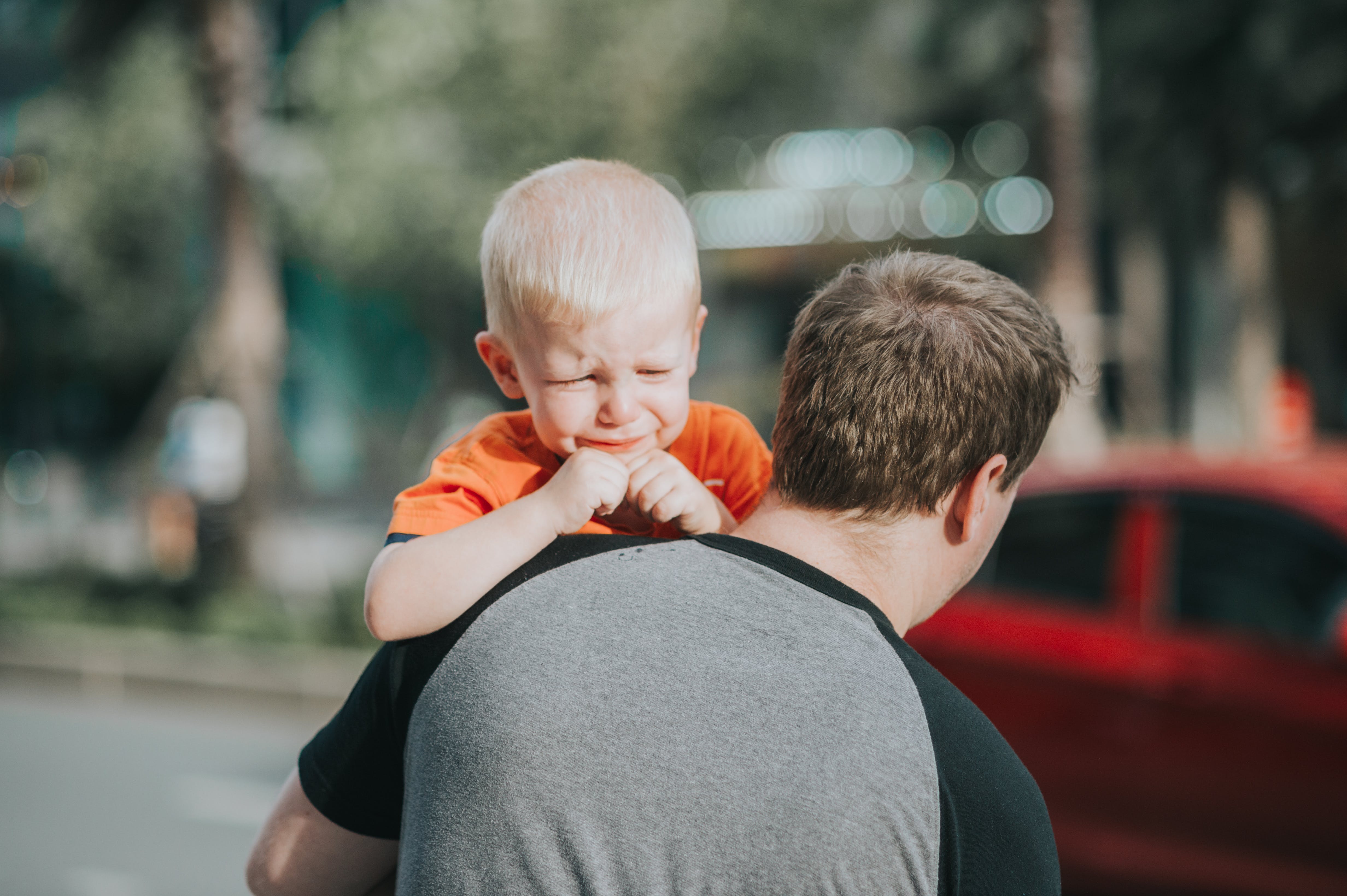 crying child carried by parent