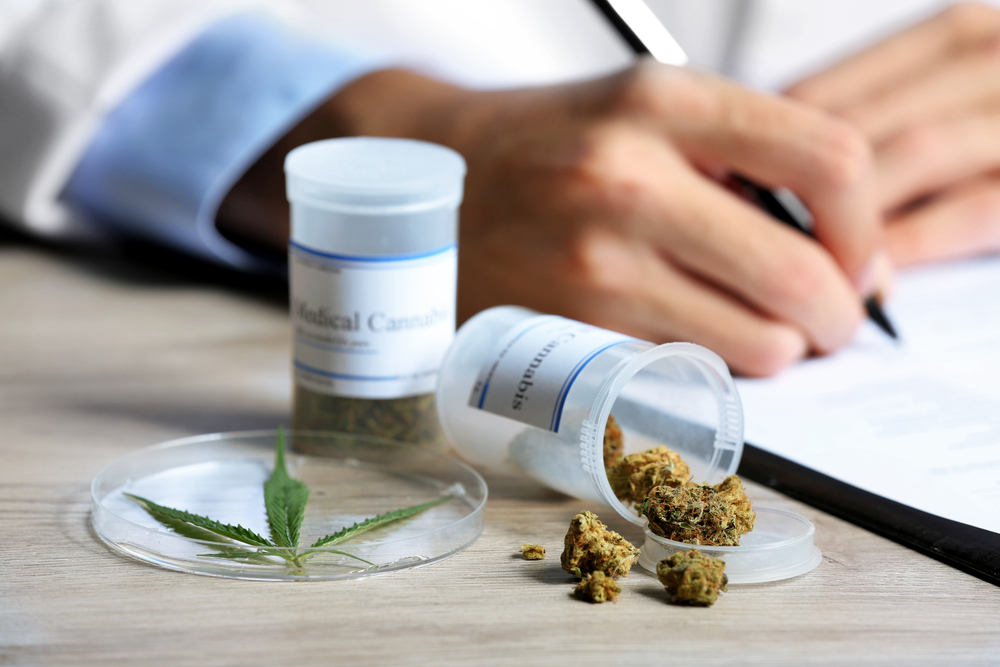 Doctor Writing Prescription Next to Container of Medical Cannabis